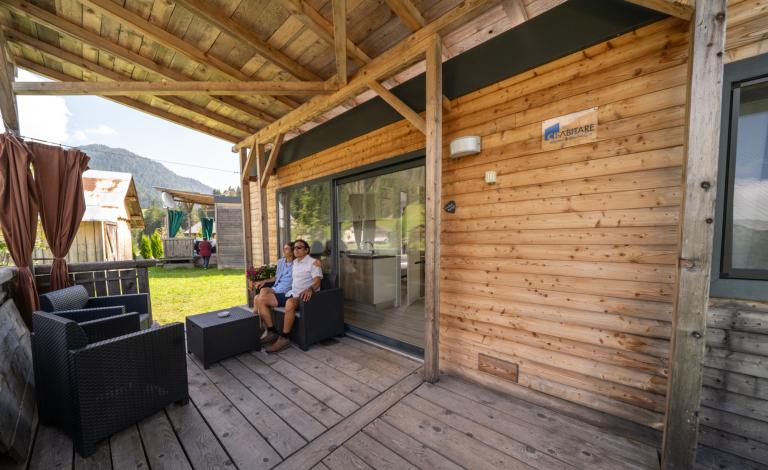 Coppia rilassata su veranda di legno, montagna sullo sfondo.