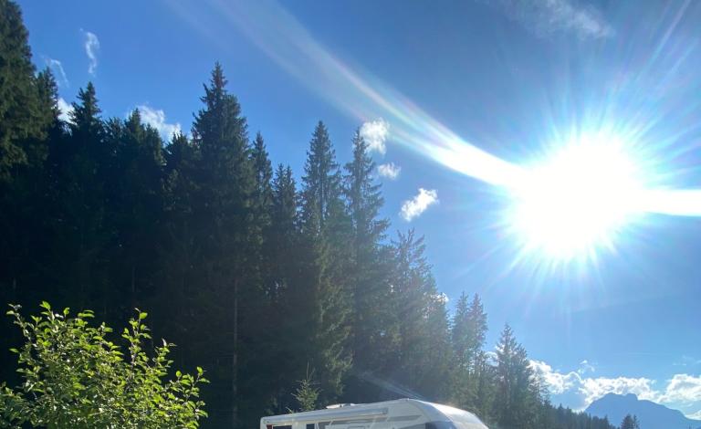 Camper immerso nella natura, sole splendente, atmosfera serena e avventurosa.