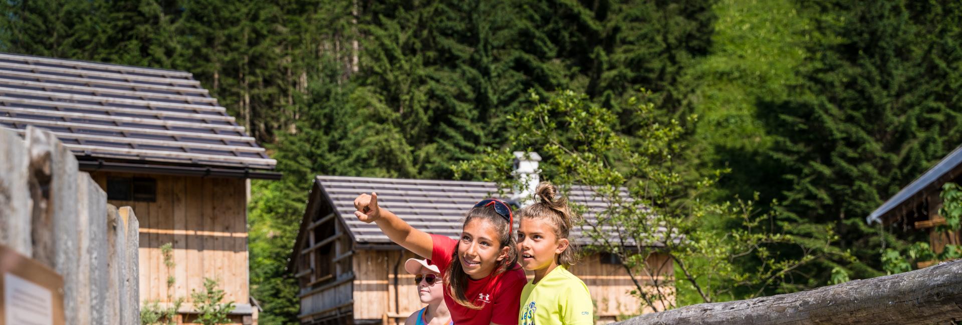 Bambini sorridenti esplorano un villaggio alpino, circondati da natura e avventura.